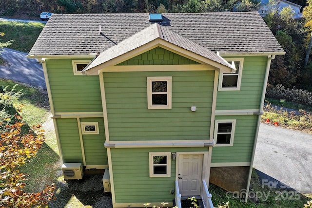 rear view of property featuring roof with shingles and ac unit