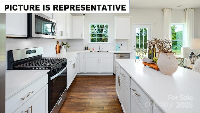 kitchen with appliances with stainless steel finishes, a sink, light countertops, white cabinets, and tasteful backsplash