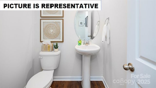 half bathroom with toilet, wood finished floors, baseboards, and a sink