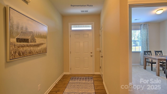 doorway featuring visible vents, baseboards, and wood finished floors