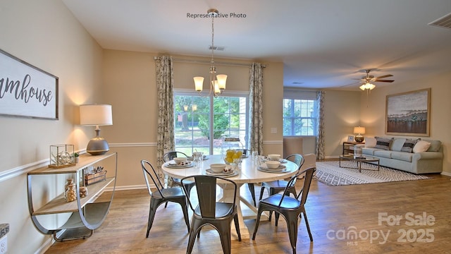 dining area with baseboards, a ceiling fan, wood finished floors, and visible vents