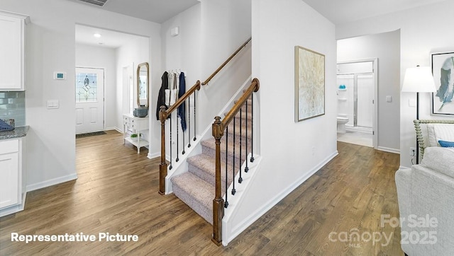 stairs featuring wood finished floors and baseboards