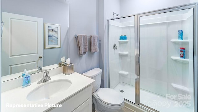 full bathroom with a stall shower, vanity, and toilet