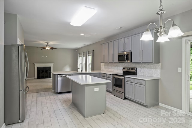 9321 Bradstreet Commons Way, Charlotte, NC 28215 - kitchen with appliances with stainless steel finishes, gray cabinetry, tasteful backsplash, a peninsula, and light countertops