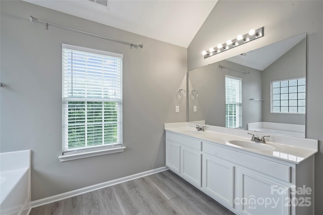 9321 Bradstreet Commons Way, Charlotte, NC 28215 - bathroom featuring vaulted ceiling, a bath, plenty of natural light, wood finished floors, and double vanity