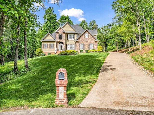 view of front of house with concrete driveway, brick siding, and a front yard