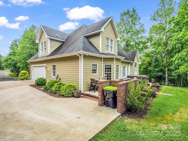 view of side of home with a garage, a shingled roof, and driveway