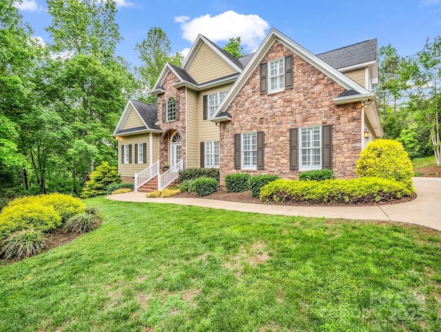 view of front of house with a shingled roof, stone siding, and a front lawn