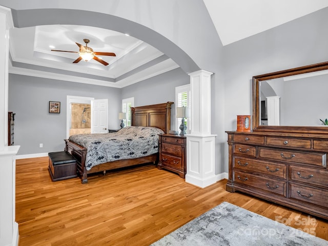bedroom featuring decorative columns, crown molding, arched walkways, baseboards, and light wood-style floors