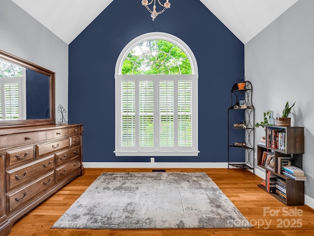 sitting room featuring baseboards, vaulted ceiling, and light wood-style floors