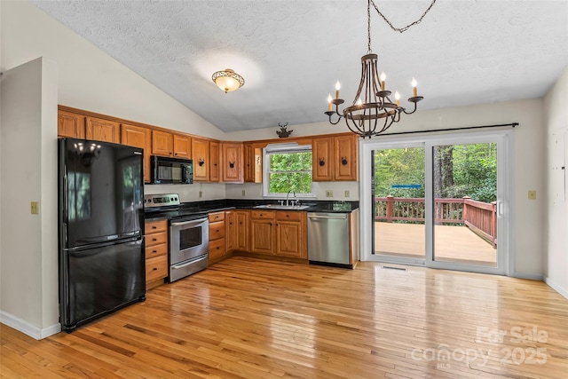 6562 Gingercake Rd, Newland, NC 28657 - kitchen with black appliances, a textured ceiling, a chandelier, dark countertops, and light wood-type flooring