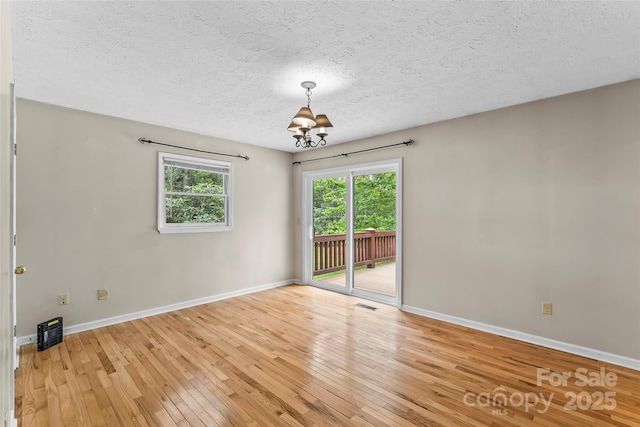 6562 Gingercake Rd, Newland, NC 28657 - empty room with light wood-style flooring, baseboards, a chandelier, and a textured ceiling
