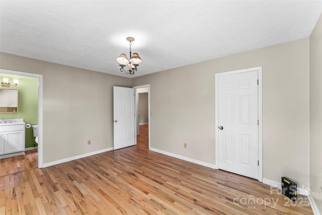 6562 Gingercake Rd, Newland, NC 28657 - unfurnished dining area with a chandelier, baseboards, light wood-type flooring, and a sink