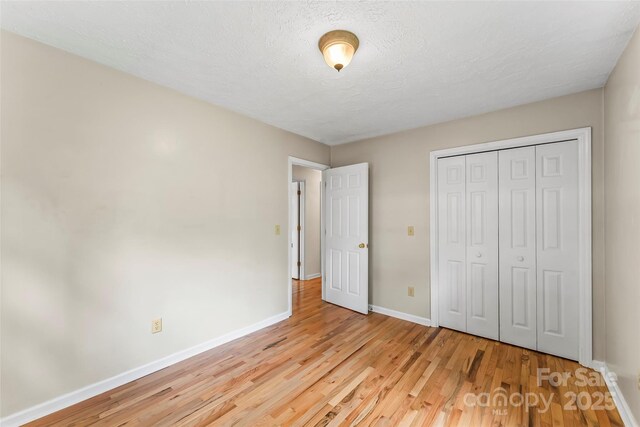 6562 Gingercake Rd, Newland, NC 28657 - unfurnished bedroom featuring wood finished floors, baseboards, a closet, and a textured ceiling