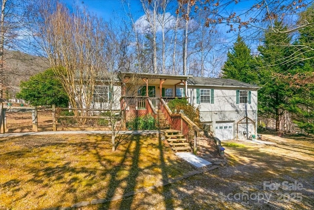 ranch-style home featuring stairway, an attached garage, covered porch, and dirt driveway