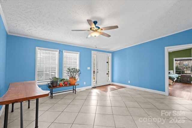 entryway with baseboards, a textured ceiling, ceiling fan, and light tile patterned flooring