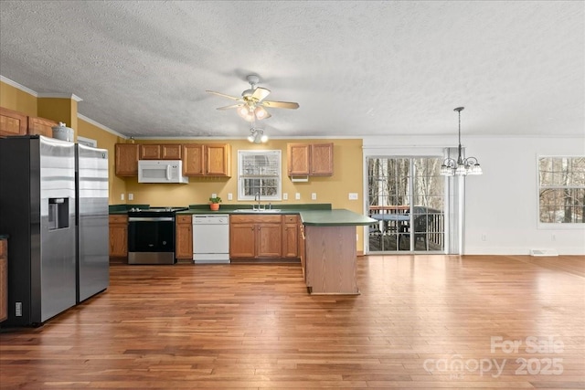 kitchen featuring a sink, ornamental molding, wood-type flooring, and stainless steel appliances