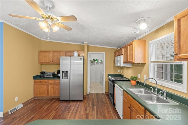 kitchen featuring visible vents, white appliances, a textured ceiling, a sink, and dark wood finished floors
