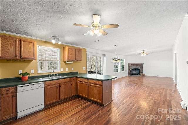kitchen with white dishwasher, ceiling fan, a sink, a textured ceiling, and a peninsula