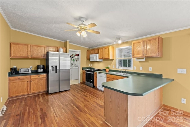 kitchen featuring a ceiling fan, a peninsula, washer / dryer, white appliances, and light wood-style flooring