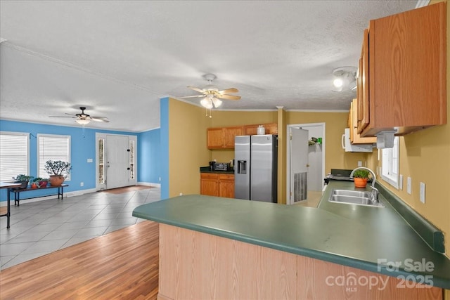 kitchen with ceiling fan, a textured ceiling, a sink, a peninsula, and stainless steel fridge