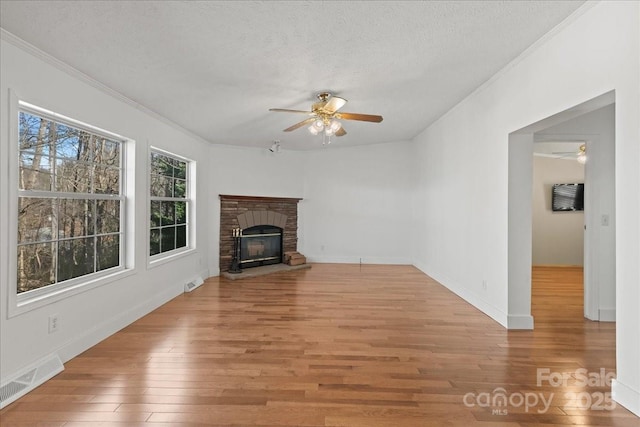 unfurnished living room featuring crown molding, a ceiling fan, light wood finished floors, and visible vents