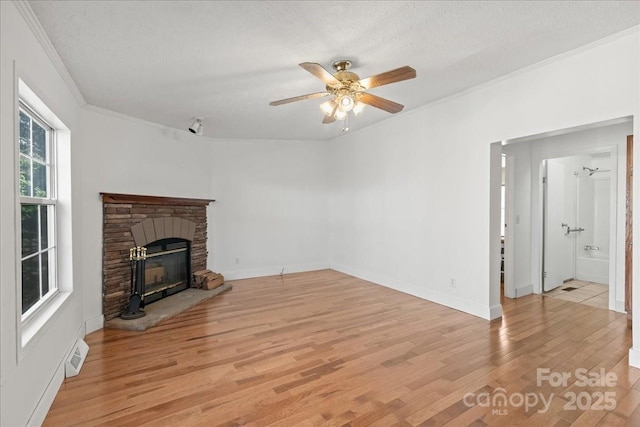 unfurnished living room featuring visible vents, ornamental molding, a brick fireplace, light wood-style floors, and a ceiling fan