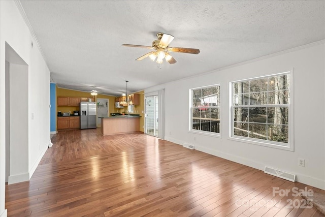 unfurnished living room with visible vents, a healthy amount of sunlight, and light wood finished floors