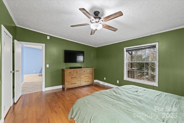 bedroom featuring visible vents, ornamental molding, a textured ceiling, and wood finished floors