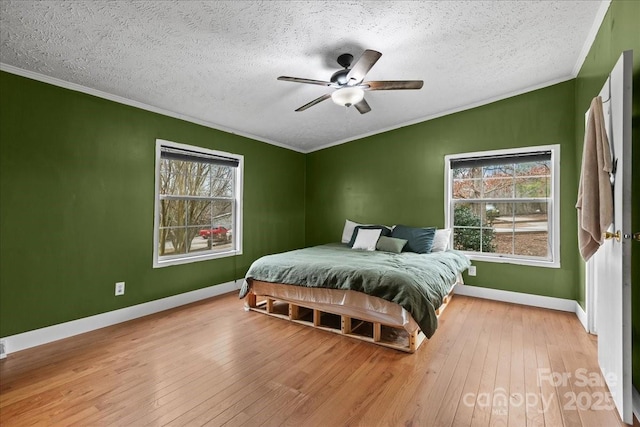 bedroom with baseboards, ornamental molding, wood-type flooring, and a textured ceiling
