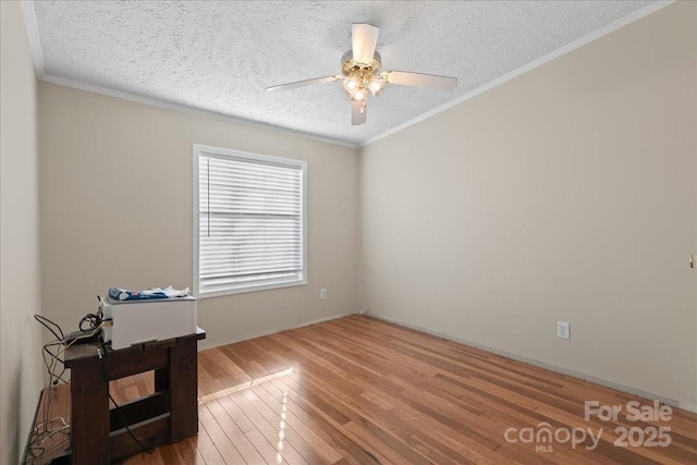 unfurnished room with a textured ceiling, ornamental molding, a ceiling fan, and wood finished floors