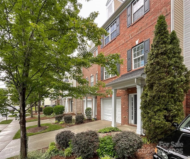 view of front of house featuring brick siding, an attached garage, and driveway