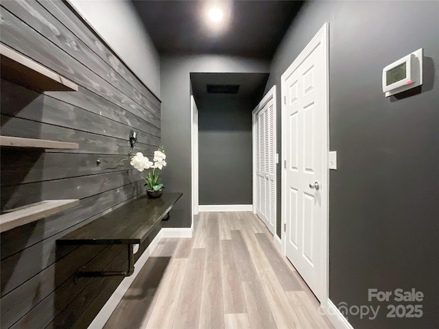 hall featuring light wood-style floors and baseboards