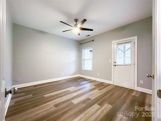 spare room featuring wood finished floors, a ceiling fan, and baseboards
