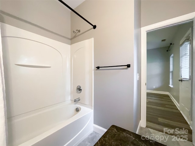 bathroom featuring baseboards and shower / tub combination