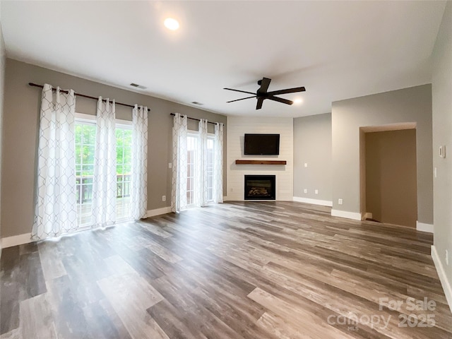 unfurnished living room with ceiling fan, a fireplace, and baseboards