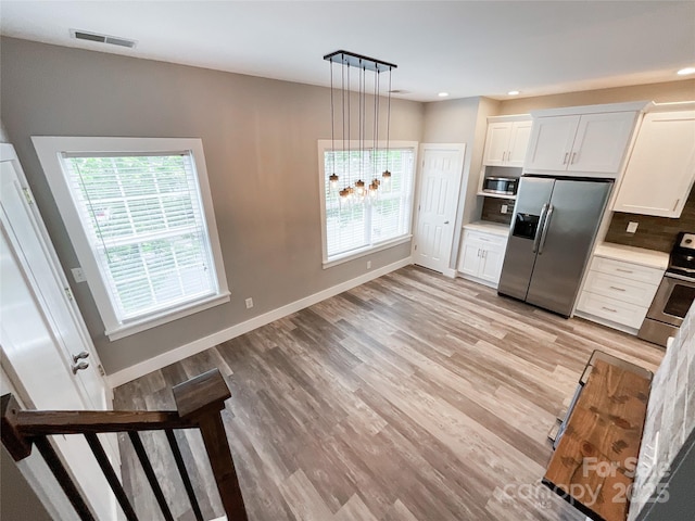 kitchen featuring appliances with stainless steel finishes, white cabinets, light wood-style flooring, light countertops, and baseboards