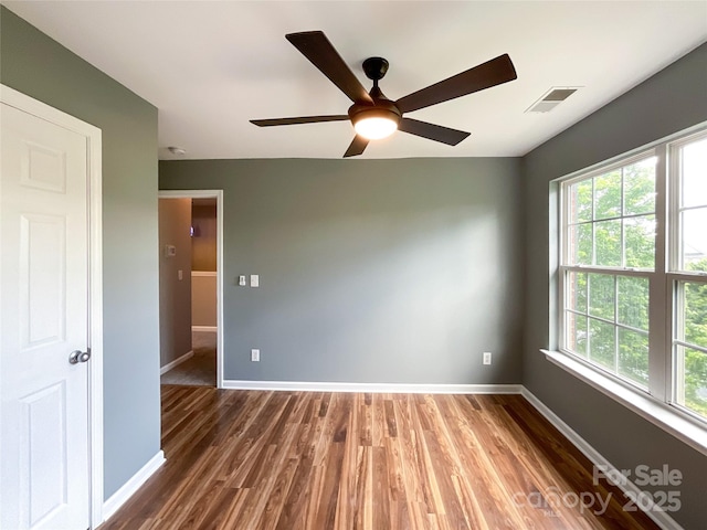 unfurnished room featuring wood finished floors, baseboards, and plenty of natural light