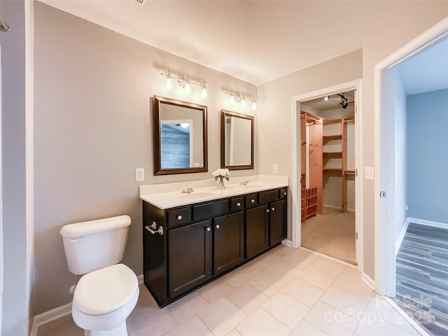 bathroom featuring tile patterned flooring, double vanity, toilet, and baseboards