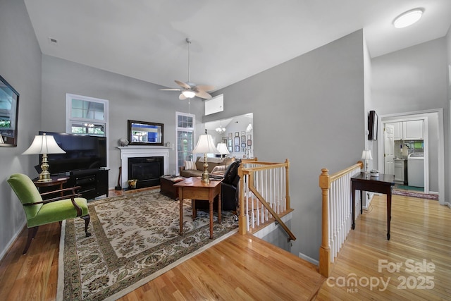 160 Fernbrook Dr, Mooresville, NC 28117 - living area featuring a towering ceiling, wood finished floors, a glass covered fireplace, a ceiling fan, and washer / clothes dryer