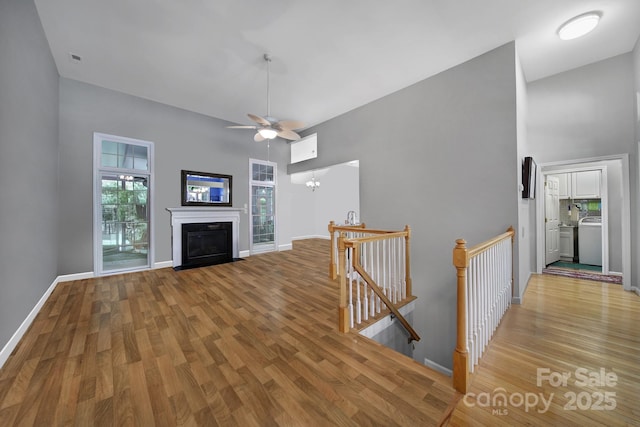 160 Fernbrook Dr, Mooresville, NC 28117 - living area featuring a high ceiling, light wood-style floors, ceiling fan, a fireplace with flush hearth, and washer / dryer