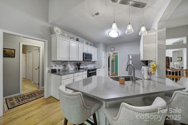 160 Fernbrook Dr, Mooresville, NC 28117 - kitchen featuring appliances with stainless steel finishes, white cabinets, light wood-style flooring, a kitchen breakfast bar, and a peninsula