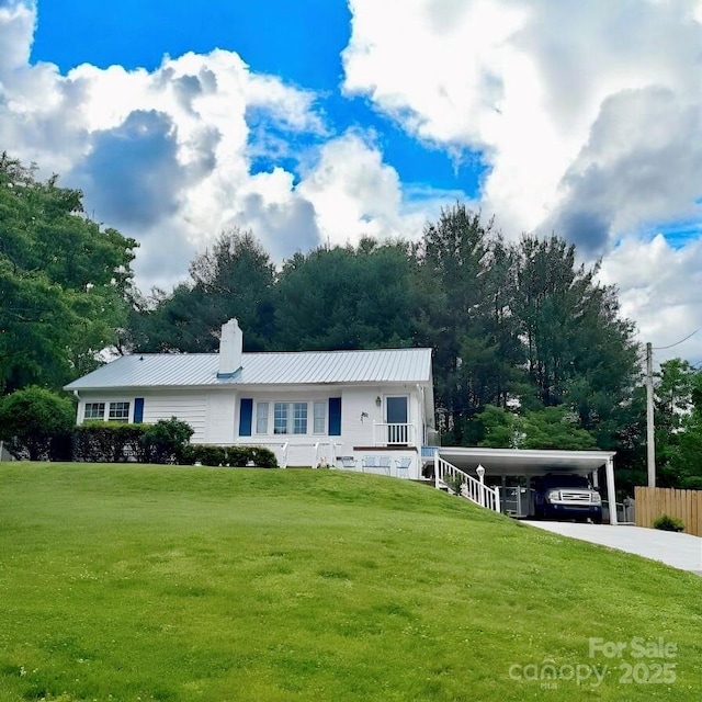 view of front of house with a chimney, driveway, metal roof, and an attached carport