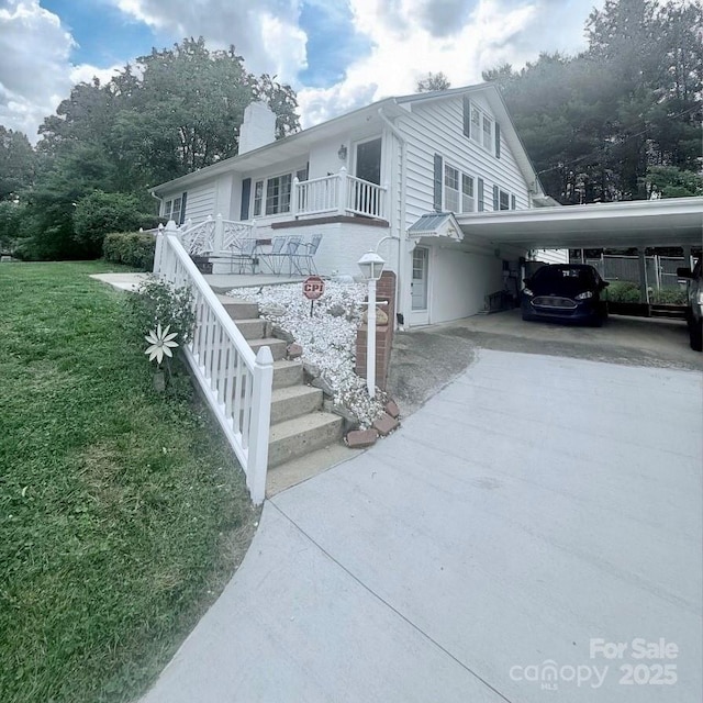 view of front of property with driveway, a chimney, a front lawn, and an attached carport