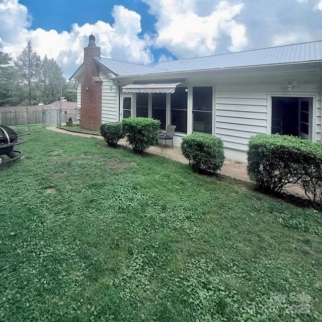 view of side of home featuring a chimney, metal roof, and a patio area
