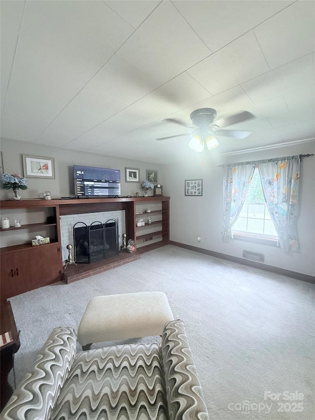 carpeted living room featuring baseboards, a ceiling fan, and a fireplace