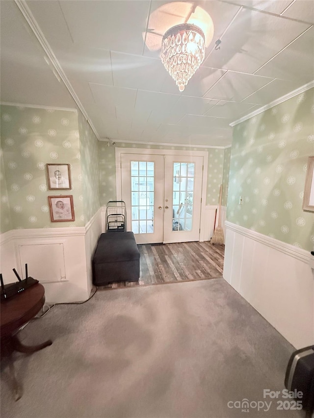 living area with ornamental molding, french doors, a wainscoted wall, wallpapered walls, and carpet floors