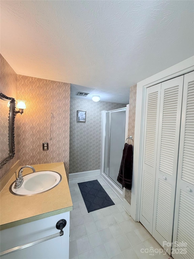 full bathroom featuring wallpapered walls, a stall shower, vanity, a closet, and baseboards