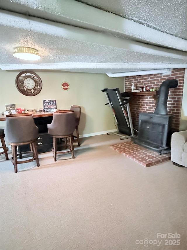 office space with a wood stove, carpet floors, a textured ceiling, and baseboards