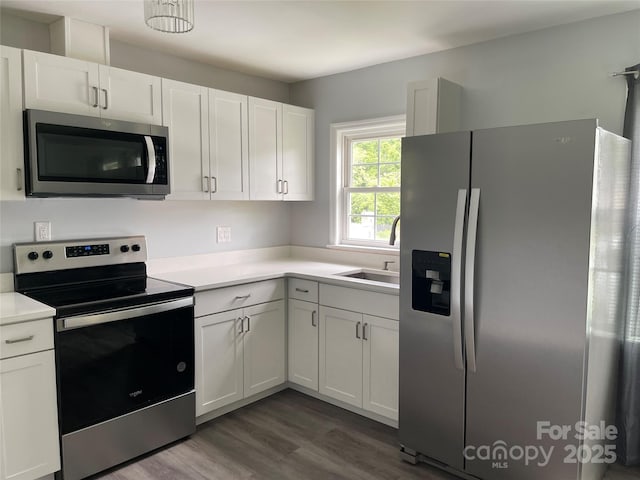 kitchen featuring a sink, stainless steel appliances, light countertops, and dark wood-type flooring